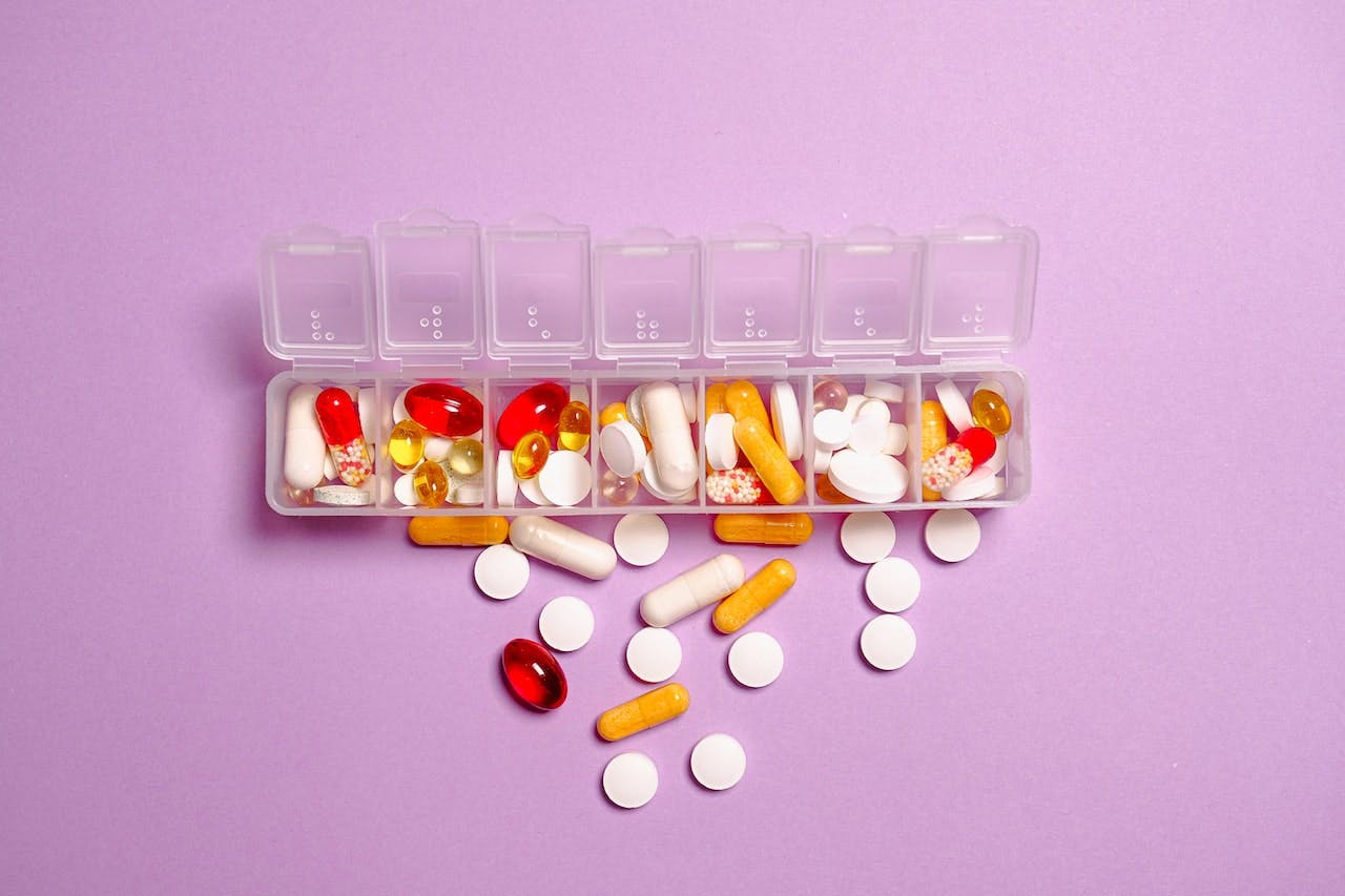 a variety of pills in a daily pill organizer stock image